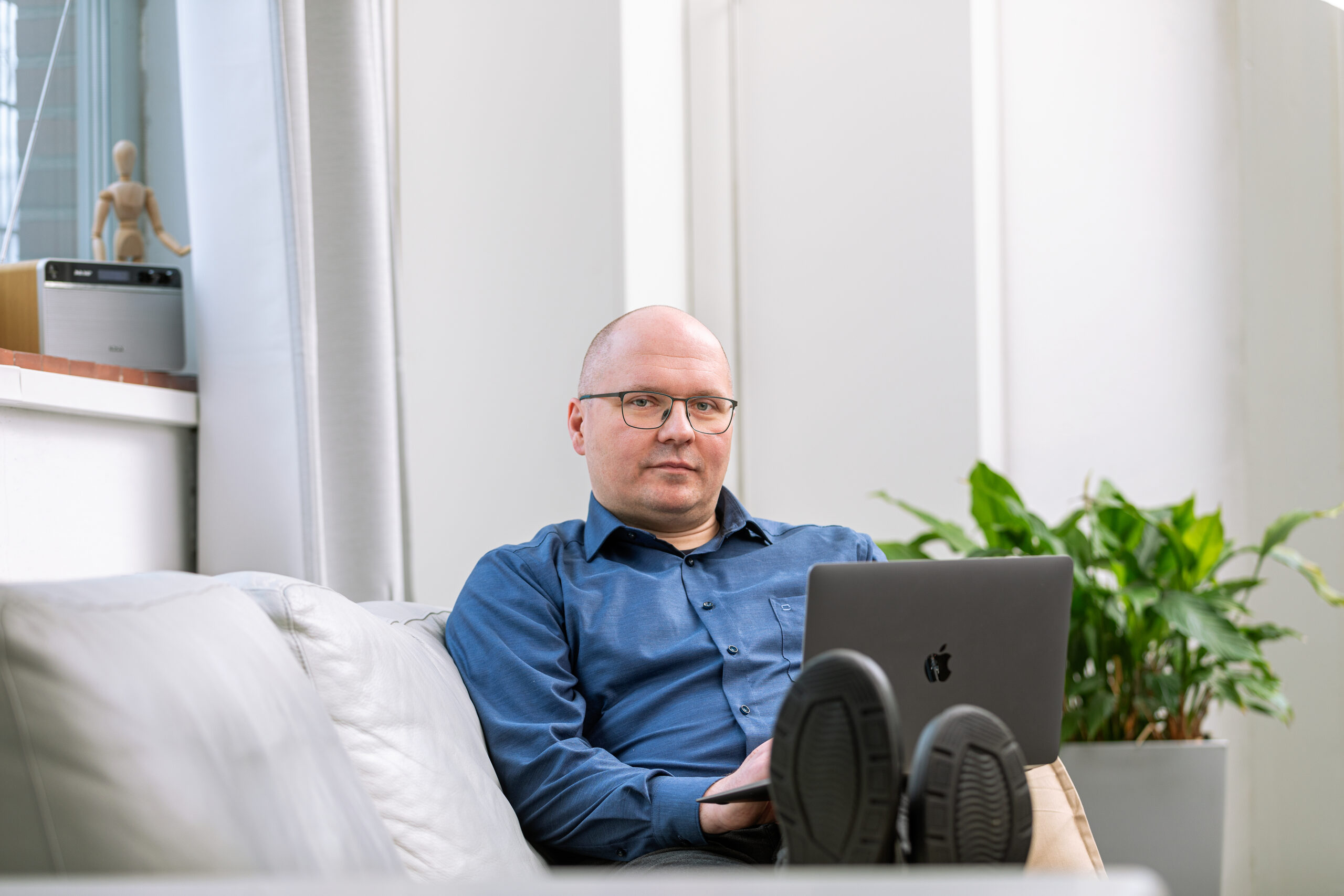 Alexander Thiele sitzt auf dem Sofa mit einem Laptop auf dem Schoß.