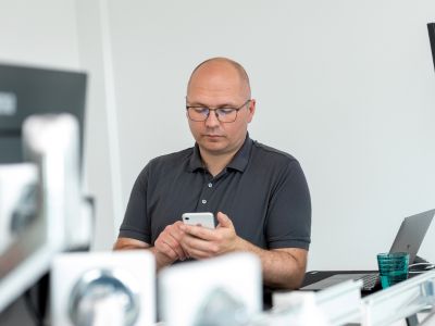 Alexander Thiele steht im Büro mit einem Handy in der Hand.